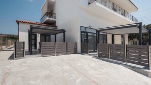 A modern building with a covered entrance, a balcony, and a gated driveway. - Ag. Ma Aggelos Suite - Chalkidiki w/ Priv Parking (Nikiti)