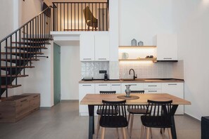 Eine moderne Küche mit einem Holzespeisetisch, schwarzen Stühlen und einer Treppe mit Geländer.