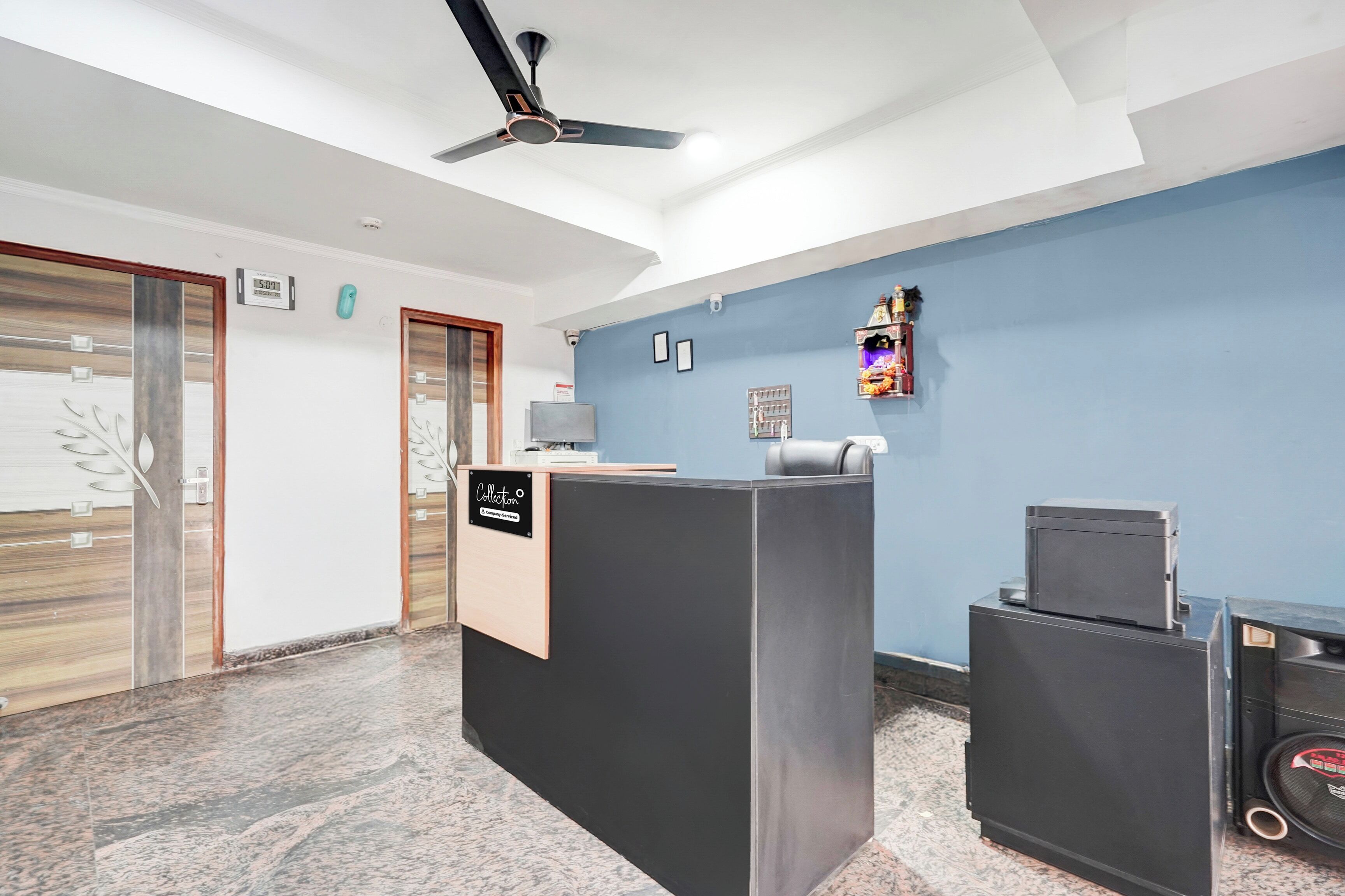 Un área de recepción con un mostrador, un reloj y un ventilador de techo.