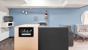 Un área de recepción con mostrador, televisión, un pequeño santuario y una zona de estar con una silla.