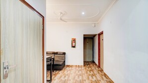 Un pasillo con piso de madera estampado, un sofá, un ventilador de techo y una puerta con número.
