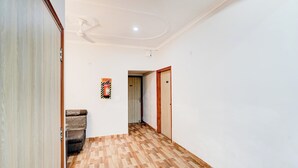Un pasillo con suelo de madera estampado, un extintor en la pared y una puerta con un número.