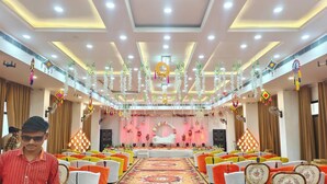 Une salle de banquet dotée d’une scène, de rangées de chaises et d’éléments décoratifs suspendus.