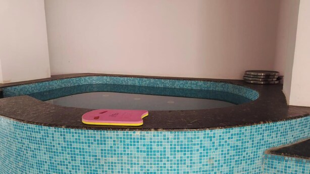 Un bain à remous avec un tapis rose, entouré d’une piscine carrelée.