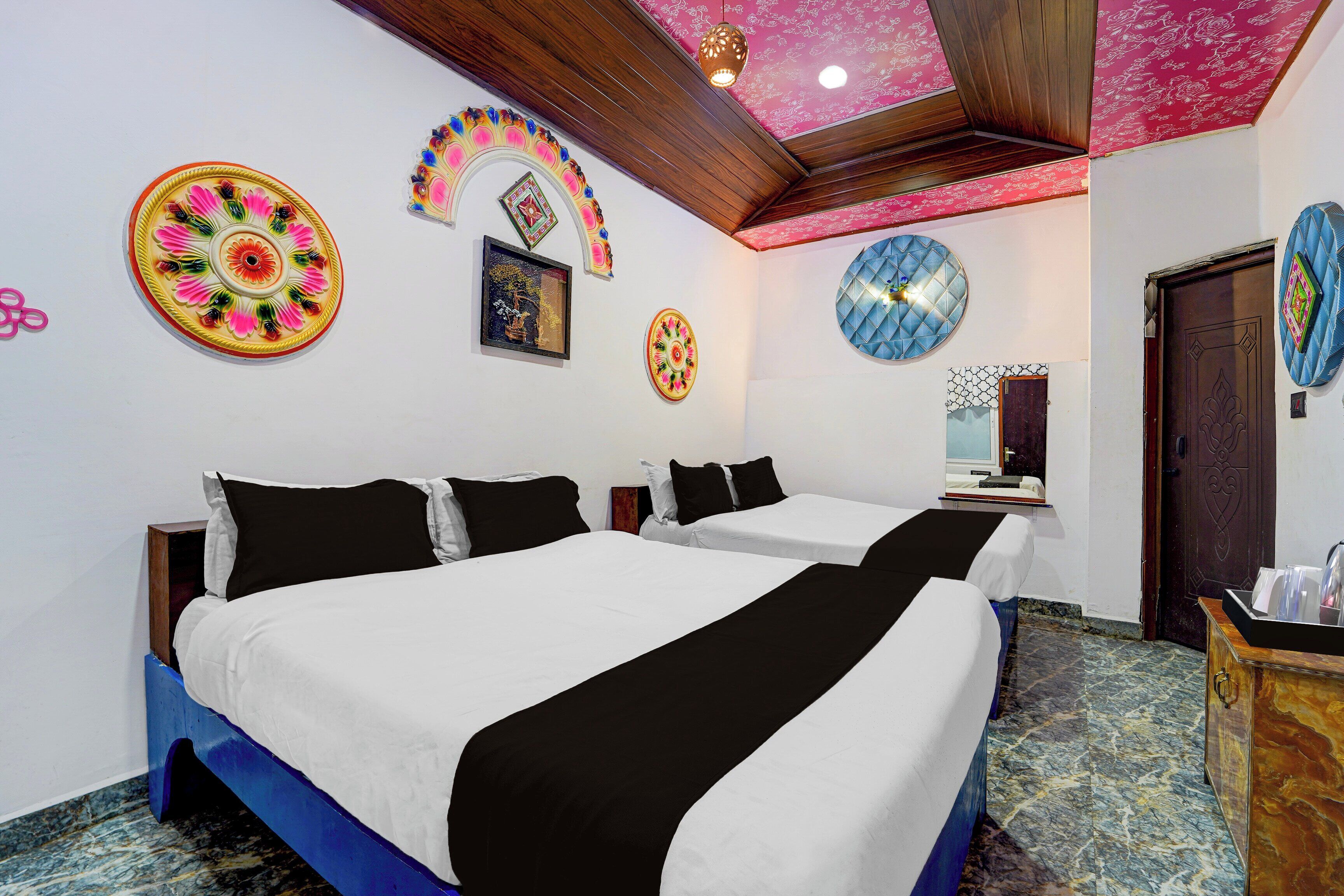 A hotel room with two beds, a wooden ceiling, and decorative wall art.
