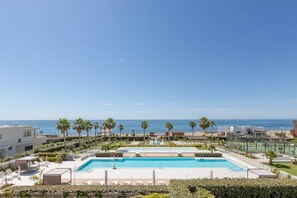 A resort with a large pool, palm trees, and a view of the ocean. - RDR574 Beachfront Luxury 4-Bed Penthouse in Velaya (Estepona)