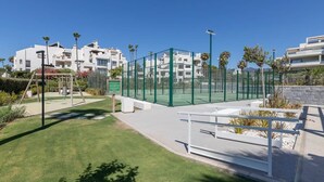 A residential complex with a tennis court, a playground, and a clear blue sky. - RDR574 Beachfront Luxury 4-Bed Penthouse in Velaya (Estepona)