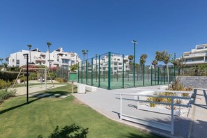 Ein Wohnkomplex mit Tennisplatz, Spielplatz und blauem Himmel.