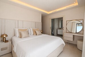 A modern bedroom with a large bed, bedside lamps, a vanity with a mirror, and a walk-in closet. - RDR574 Beachfront Luxury 4-Bed Penthouse in Velaya (Estepona)