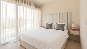 A hotel room with a large bed, two bedside tables, a nightstand, and sheer curtains. - RDR574 Beachfront Luxury 4-Bed Penthouse in Velaya (Estepona)