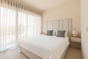 Ein Hotelzimmer mit einem großen Bett, zwei Nachttischen und leichtem Vorhang.