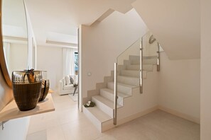 A modern interior with a staircase, a sofa, and a glass coffee table. - RDR574 Beachfront Luxury 4-Bed Penthouse in Velaya (Estepona)
