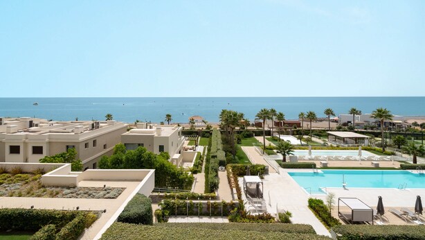 A resort with a pool, palm trees, and a view of the sea. - RDR574 Beachfront Luxury 4-Bed Penthouse in Velaya (Estepona)