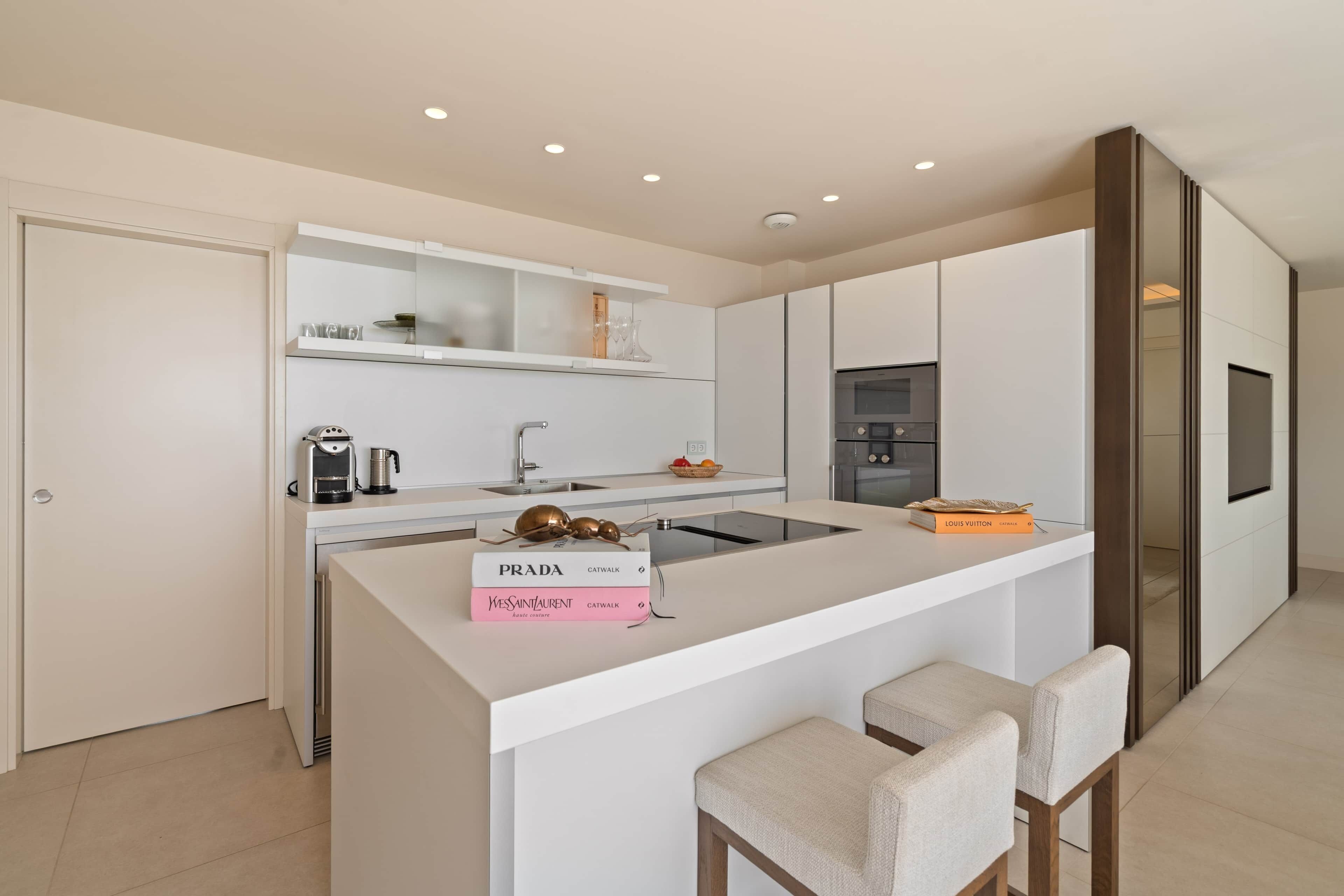 Une cuisine moderne dotée d’un îlot central, d’appareils électroménagers intégrés et d’un design minimaliste.