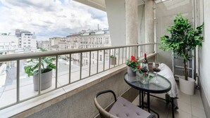 Ein Balkon mit Glastisch, Blumentöpfen und Blick auf Stadtgebäude.