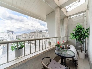 A balcony with a glass table, potted plants, and a view of city buildings. - House in Saint-pabu Near Stunning Beaches (Warsaw)