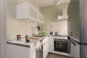A modern kitchen with white cabinetry, a Bosch oven, and a coffee maker. - Locanda della Porta 1 (Guastalla)