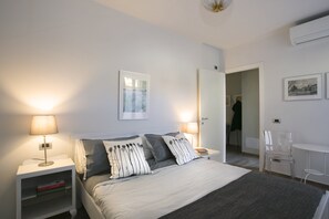 A bedroom with a bed, bedside tables, a lamp, a framed picture, and a chair. - Locanda della Porta 1 (Guastalla)