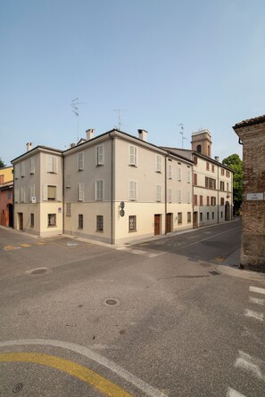 A street view with a row of buildings, including a two-story structure with a flat roof and multiple windows. - Locanda della Porta 1 (Guastalla)
