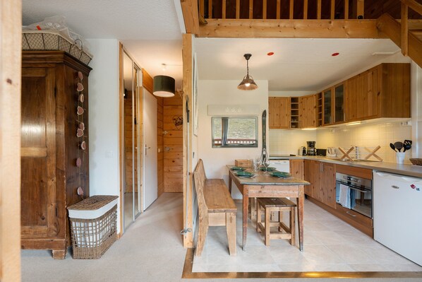 A cozy kitchen with wooden cabinets, a dining table with benches, and a built-in oven.