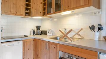 A modern kitchen with wooden cabinets, a stainless steel sink, and a built-in oven.