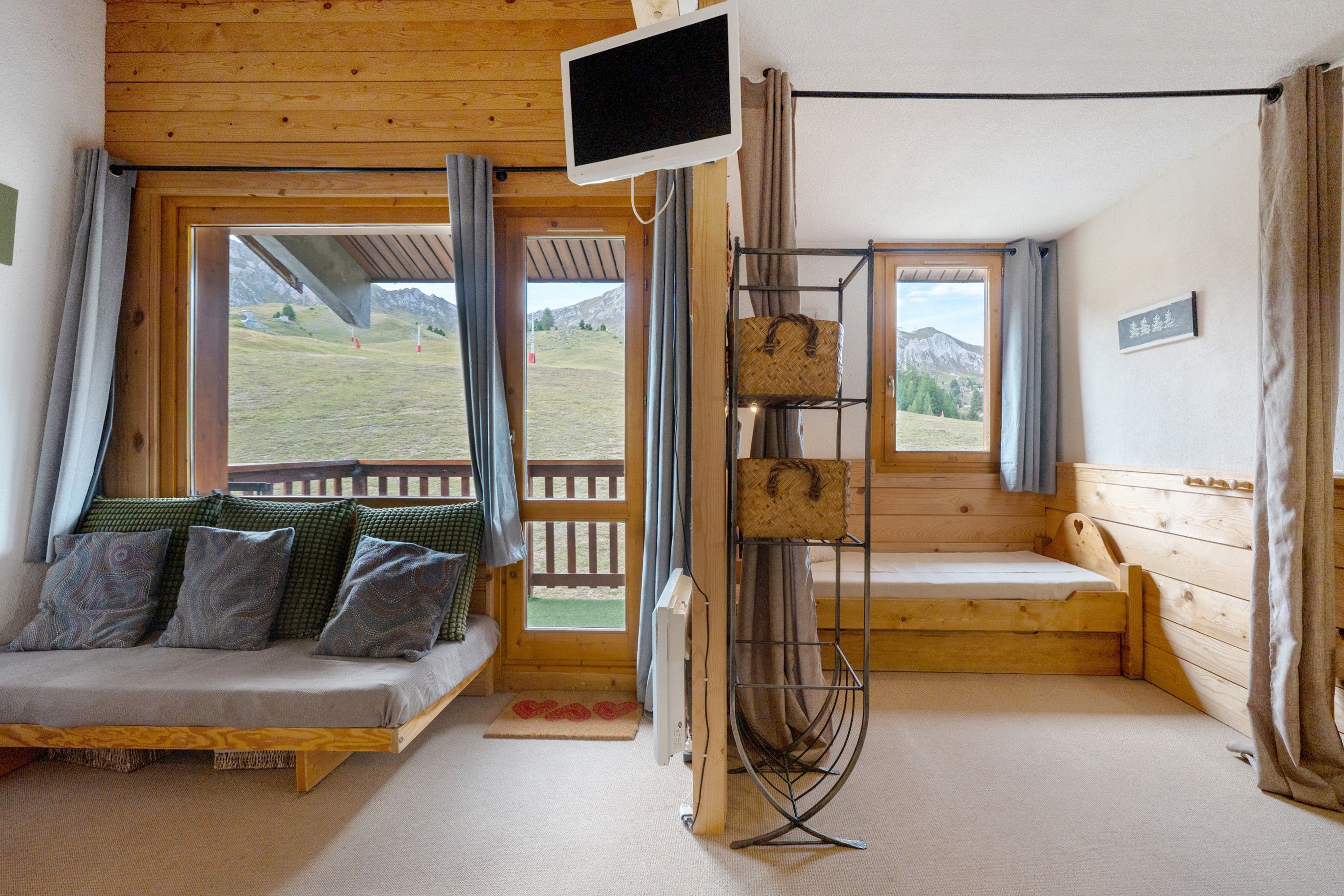 Una habitación acogedora con una cama de madera, un televisor y vistas a la montaña.