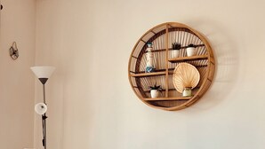 Un comedor con una mesa redonda de madera, dos sillas, un adorno en la pared y una lámpara de pie.