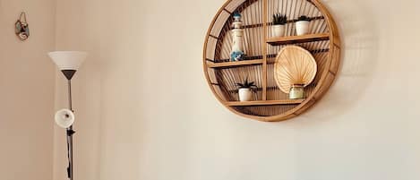 A dining area with a round wooden table, two chairs, a wall-mounted decorative piece, and a floor lamp.