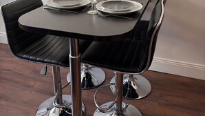 A dining table with four chairs, a pitcher, and wine glasses set for four.