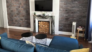 A living room with a fireplace, a flat-screen TV, and a modern stone wall design.
