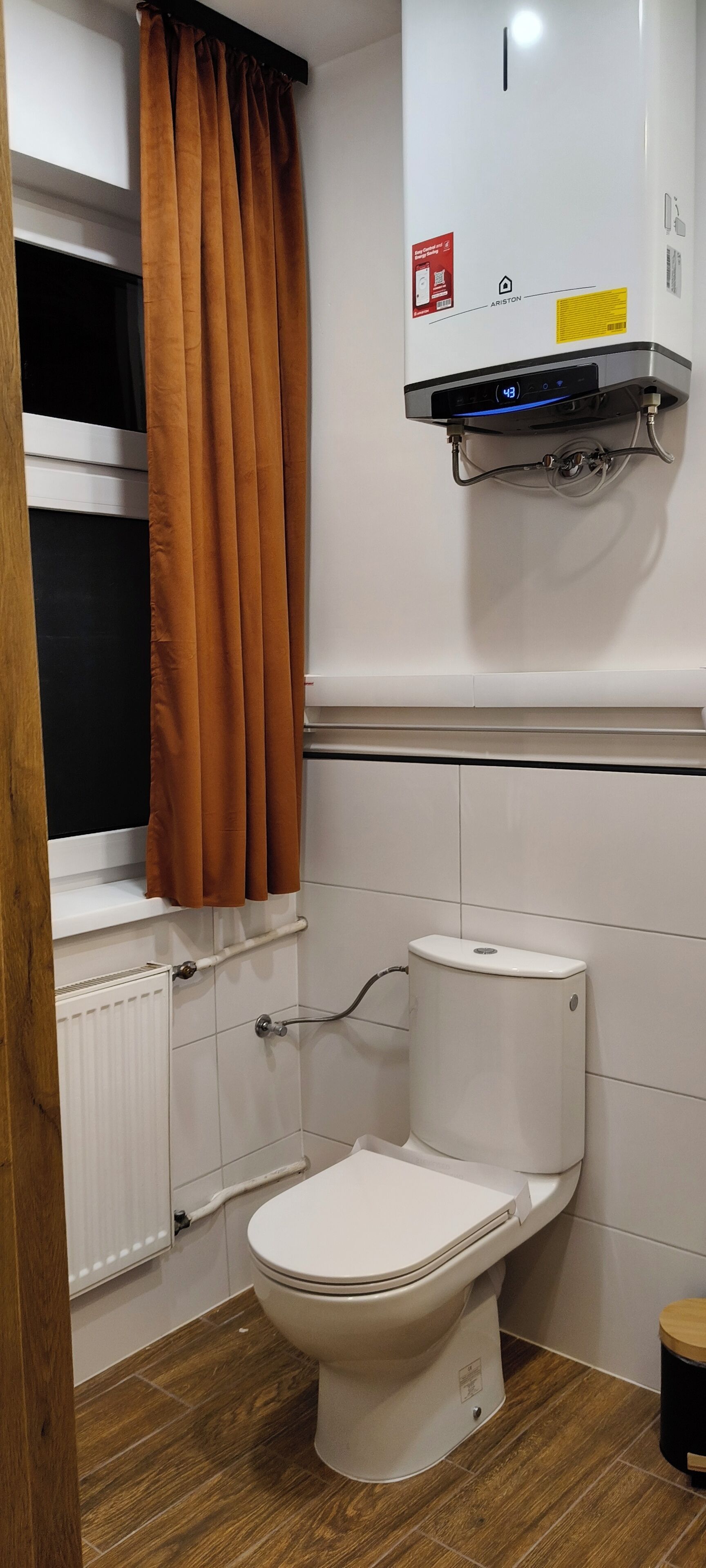 Ein Badezimmer mit Toilette, Heizkörper und Wandheizung.