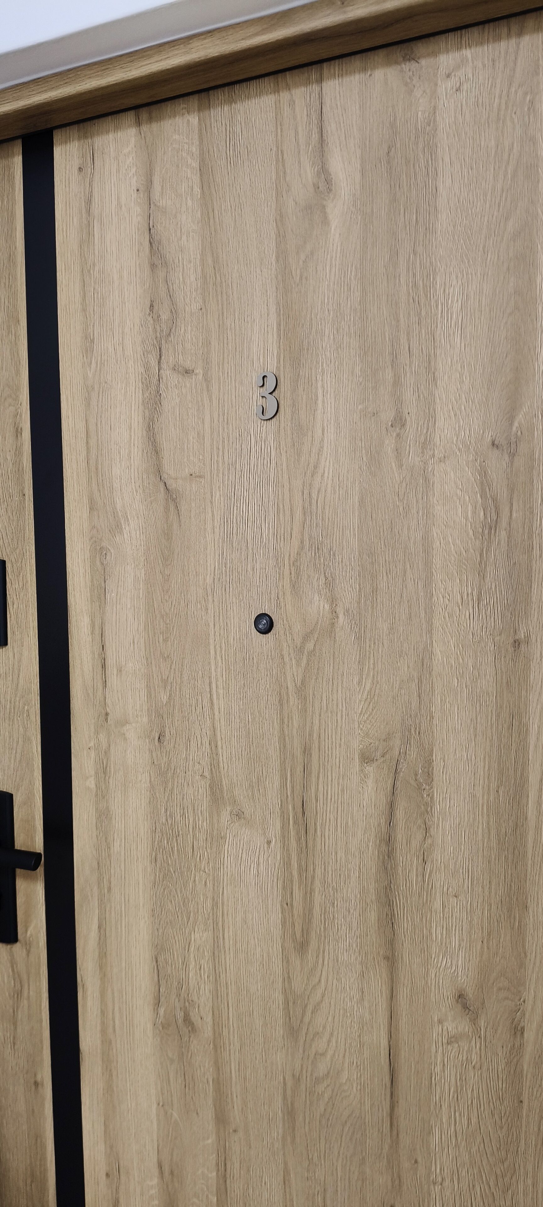 A wooden door with a number '3' and a small circular object on it.