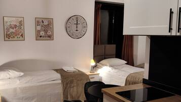 Habitación de hotel con dos camas, un escritorio, una lámpara, un reloj y una televisión.