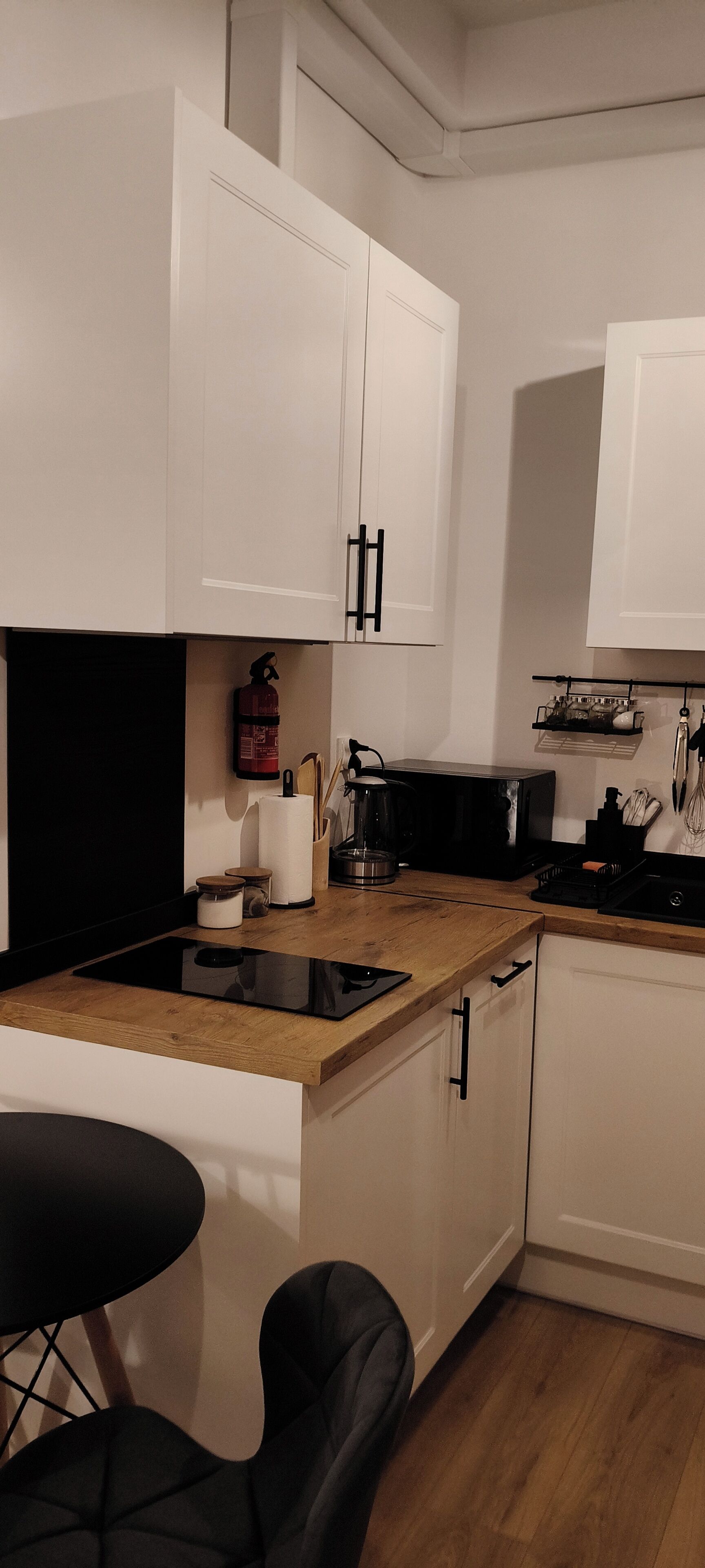A modern kitchen with white cabinets, a black countertop, a coffee maker, and a microwave.