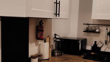 A modern kitchen with white cabinets, a black countertop, a coffee maker, and a microwave.