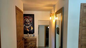 A hallway with a wooden dresser, a large mirror, and a painting on the wall.