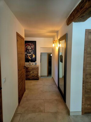 A hallway with a wooden dresser, a large mirror, and a painting on the wall.