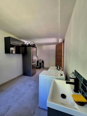 Cocina compacta con refrigerador, lavadora y un lavamanos con una esponja.