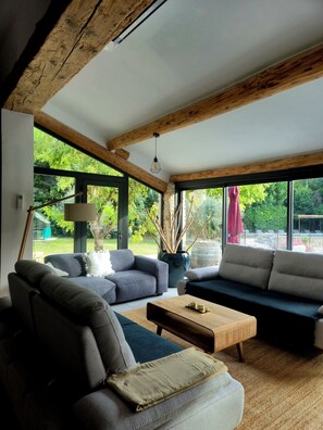 Un salon moderne avec un canapé, une table basse et une grande fenêtre donnant sur l’extérieur.