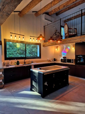 A modern kitchen with a central island, pendant lighting, and a view of greenery outside. - Mas La Fontaine de Pernes, les pieds dans la Sorgue, piscine, 12p, 6ch, 5sdb (Pernes-les-Fontaines)