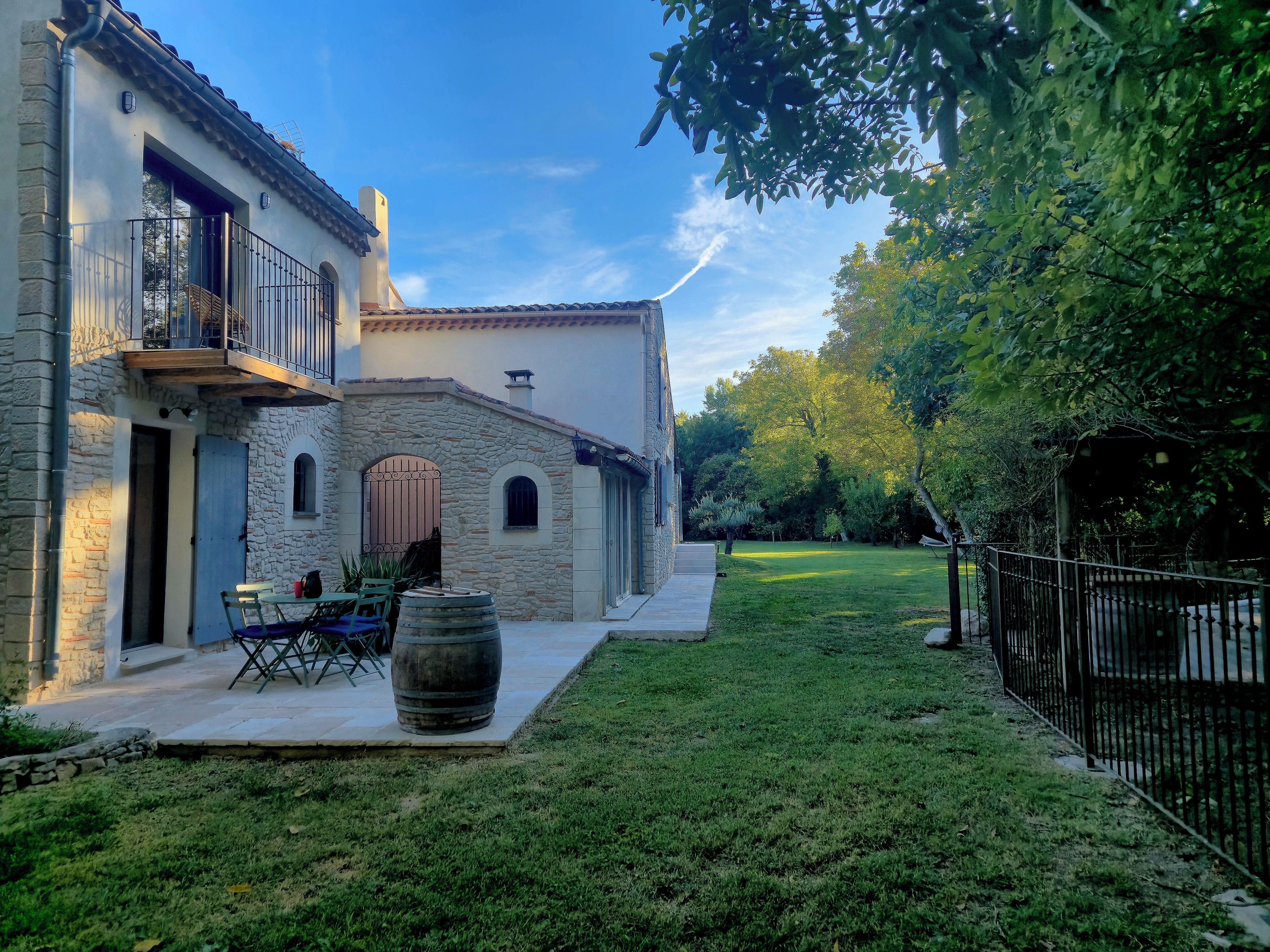 Un bâtiment en pierre doté d’un balcon, d’une cour gazonnée et d’une clôture.