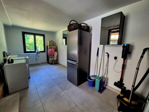 Una cocina con refrigerador, microondas, lavamanos y ventana con vista a la vegetación.