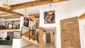A spacious interior with a wooden staircase, a large decorative door, and artwork on the walls. - Mas La Fontaine de Pernes, les pieds dans la Sorgue, piscine, 12p, 6ch, 5sdb (Pernes-les-Fontaines)