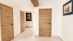 A hallway with wooden doors, a rug, and artwork on the walls. - Mas La Fontaine de Pernes, les pieds dans la Sorgue, piscine, 12p, 6ch, 5sdb (Pernes-les-Fontaines)