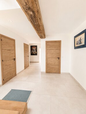 A hallway with wooden doors, a rug, and artwork on the walls.