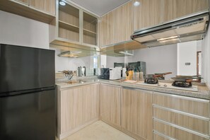 Eine moderne Küche mit einem Edelstahl-Kühlschrank, Holzschränken, einer Granit-Arbeitsplatte und einem eingebauten Herd.