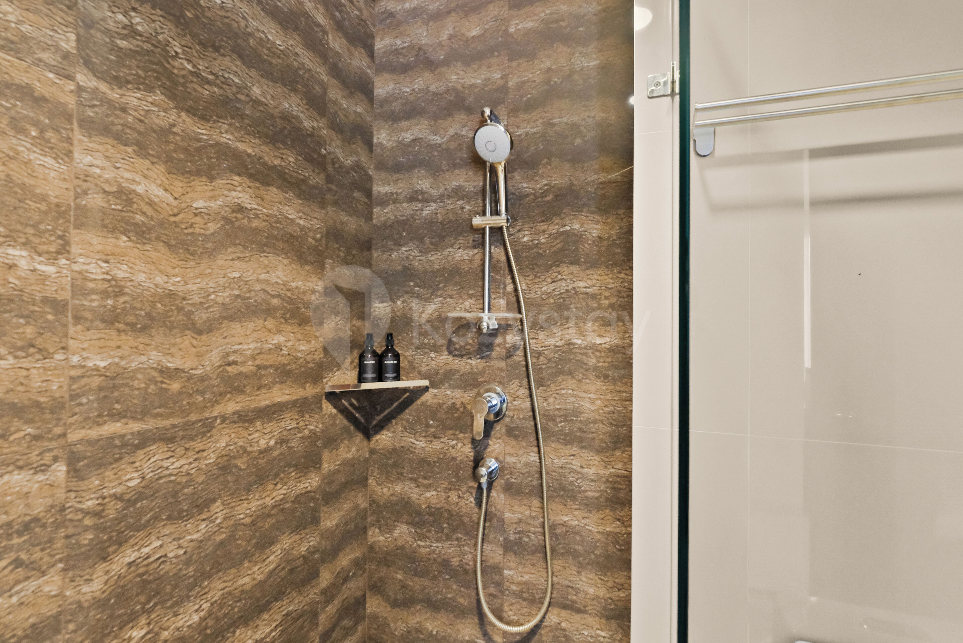 A bathroom with a shower, a towel rack, and a shelf with bottles.