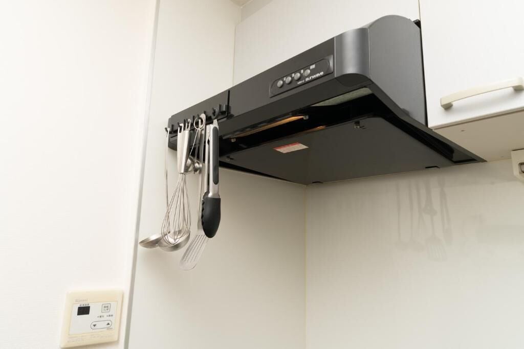 Een keuken met een inbouwoven en diverse keukengerei erboven.
