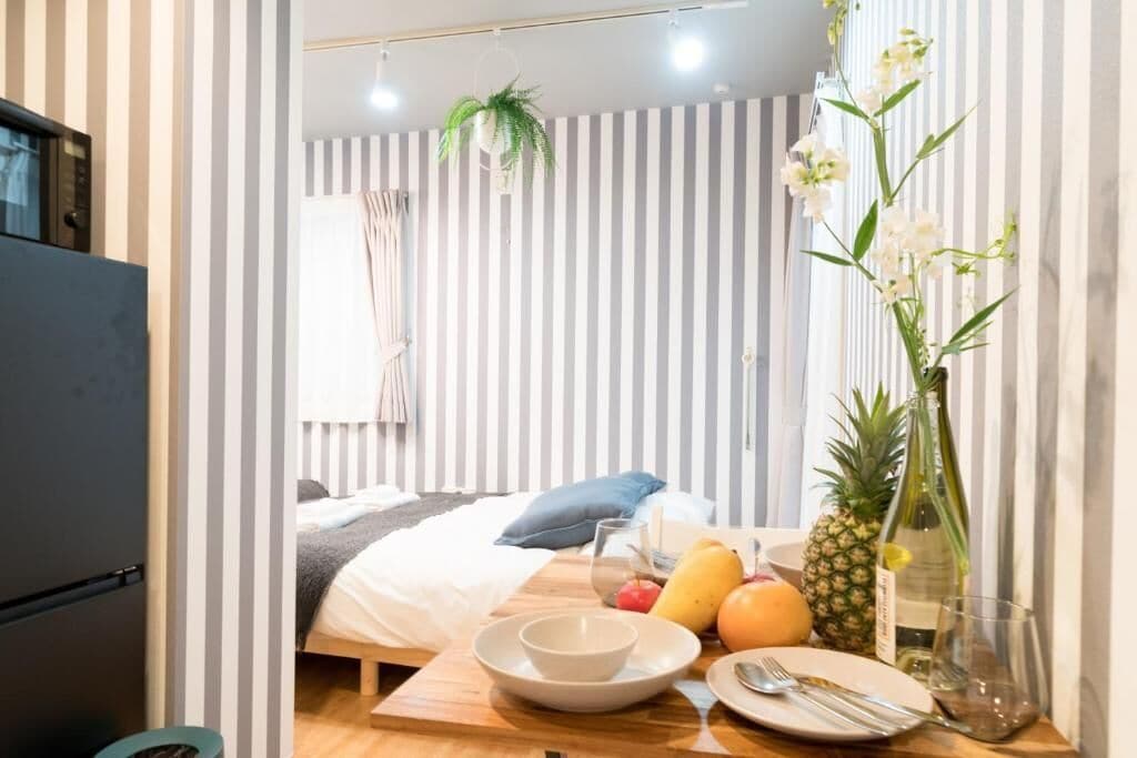 Een hotelkamer met een bed, een ontbijttafel met fruit en een fles, en een plant.