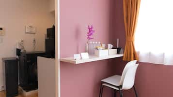 Une pièce comprenant un bureau, une chaise, un lave-linge et une petite étagère avec quelques objets.
